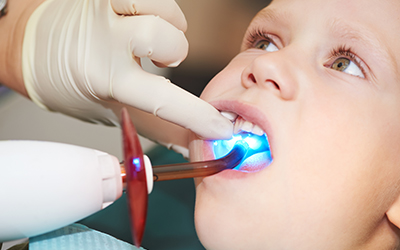 Child in dental chair with curring light