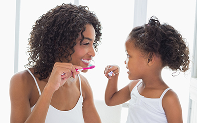 A mother and child brushing their teeth together