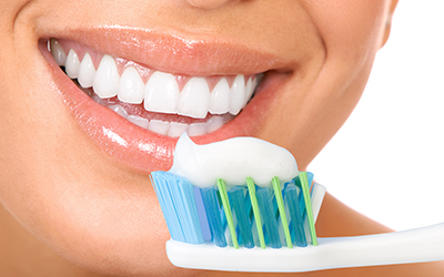 Close-up of healthy smile and a toothbrush with toothpaste on it
