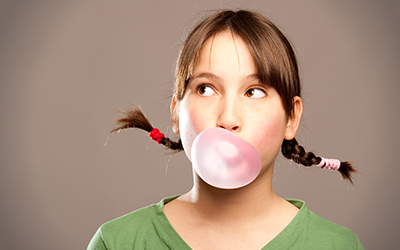 A girl blowing a bubble with her chewing gum
