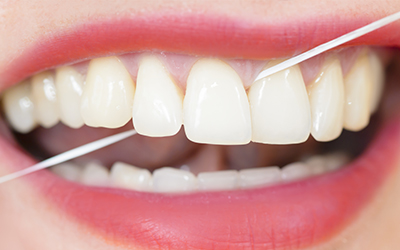 an up-close mouth using dental floss