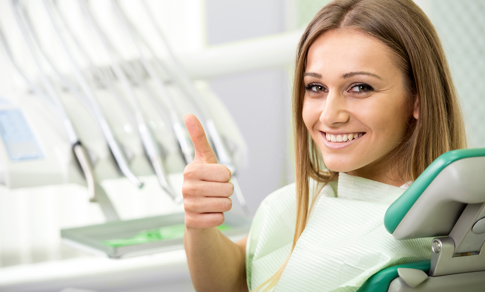 Young lady in dental chair with thumbs up